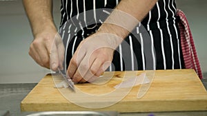 professional chef slices raw white fish with a knife in close-up, thin slices. A chef preparing seafood dishes.