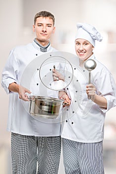 professional chefs with a pan and a ladle in a commercial kitchen