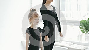 Professional cherleading trainer dancing with little girl, moving synchronically at dance class