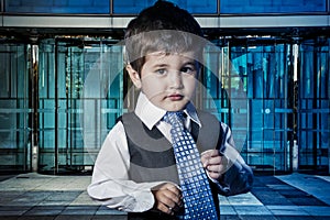 Professional, child dressed businessman with hands in his tie an