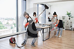 Professional cleaner Caucasian man having fun holding vacuum cleaner like guitar