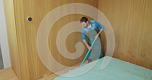 Professional cleaner in uniform washing floor in the hotel room or apartment bedroom. Cleaning service concept.