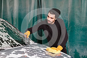 A professional cleaner washes a grey car