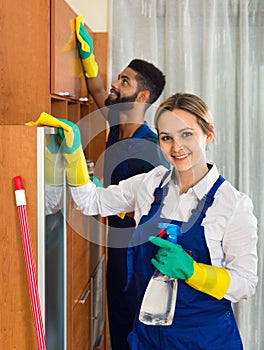 Professional cleaners cleaning and dusting in house