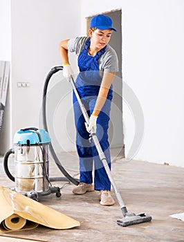 Professional cleaning after renovation in the room - woman vacuums the floor