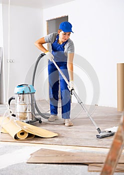 Professional cleaning after renovation in the room - woman vacuums the floor