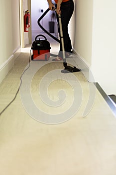 Professional cleaning service. Woman hoovering carpet in office