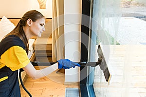 professional cleaning service. woman in uniform and gloves sponge washes panoramic windows in the cottage. washing steam