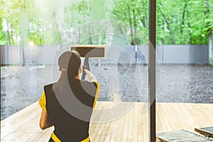 professional cleaning service. woman in uniform and gloves sponge washes panoramic windows in the cottage. washing steam