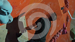 A professional climber trains on a climbing wall in an indoor gym