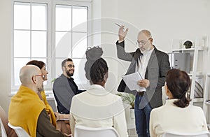 Professional coach or mentor talking to team of employees during business training