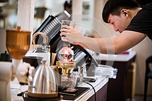 Professional coffee maker - Barista using coffee siphon brewing hot espresso at coffee shop