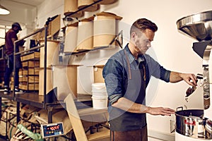 Professional coffee roaster operating a roasting machine in dist