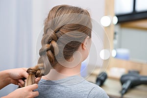 Professional coiffeuse braiding client`s hair