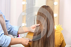 Professional coiffeuse combing client`s hair