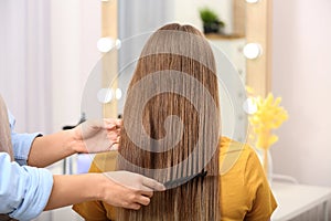 Professional coiffeuse combing client`s hair