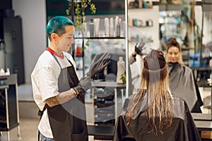 Professional colorist putting on gloves before coloring hair in beauty salon
