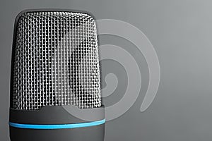 Professional condenser microphone on grey background, closeup with space for text