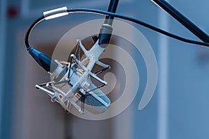 A professional condenser microphone mounted on a tripod set up in a concert hall.