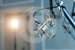 A professional condenser microphone mounted on a tripod set up in a concert hall with spot lighting.