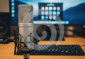 Professional condenser microphone in a recording studio with computer and keyboard creating audio content