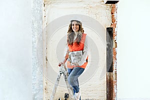 Professional confident architect woman in construction site standing on ladder. Home renovation
