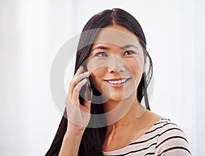 Professional connections. An attractive young asian woman using her mobile phone while indoors.