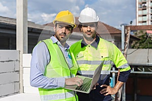 Professional construction engineer team, Two man engineer wear uniform holding laptop looking at camera standing at construction