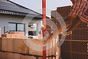 Professional construction worker adjusting bricks and mortar - building house wall