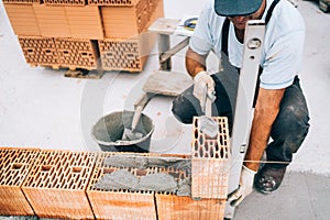 Professional construction worker building walls and bricklaying rows of bricks