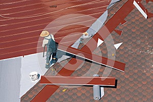 Professional construction worker changing the roof membrane of a building with metal roof sheet.