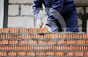 professional construction worker laying bricks and building house on industrial site