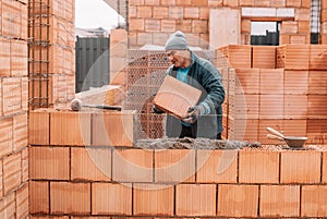 Professional construction worker laying bricks and building walls at industrial site