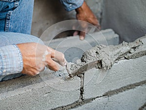 Professional construction worker laying bricks with cement