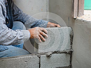 Professional construction worker laying bricks with cement