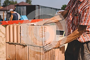 Professional construction worker laying bricks and mortar - building house wall