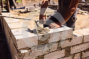 Professional construction worker laying bricks and mortar - building house wall