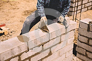 Professional construction worker laying bricks and mortar - building house wall