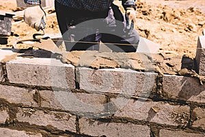 Professional construction worker laying bricks and mortar - building house wall