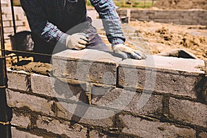 Professional construction worker laying bricks and mortar - building house wall