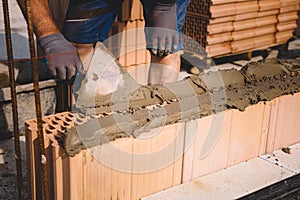 Professional construction worker laying bricks and mortar - building house wall