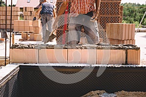 Professional construction worker laying bricks and mortar - building house wall