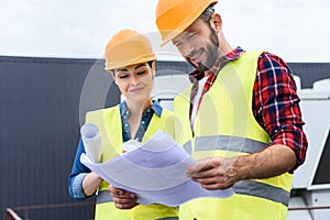 professional constructors in hardhats working with blueprints