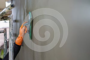 Professional contractor plastering wall with sponge float to make a smooth rendering