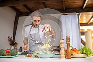 Professional cook putting cabbage into a salad