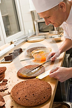 Professional cook spreading jam on cake