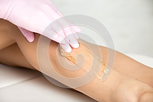 Professional cosmetician undergoing waxing procedure