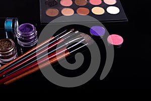 Professional cosmetics and brushes for make-up on a black background