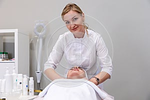 Professional cosmetologist does facial rejuvenation massage for woman. Salon anti-aging procedures