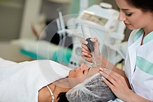 Professional cosmetologist undergoing darsonvalization on skin o photo